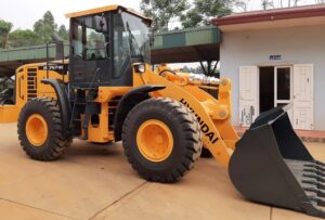 Pá carregadeira Hyundai HL757-9S amarela com caçamba frontal em área externa