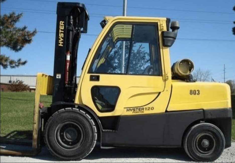Empilhadeira Hyster amarela com cabine fechada, mastro preto e garfos em ambiente externo